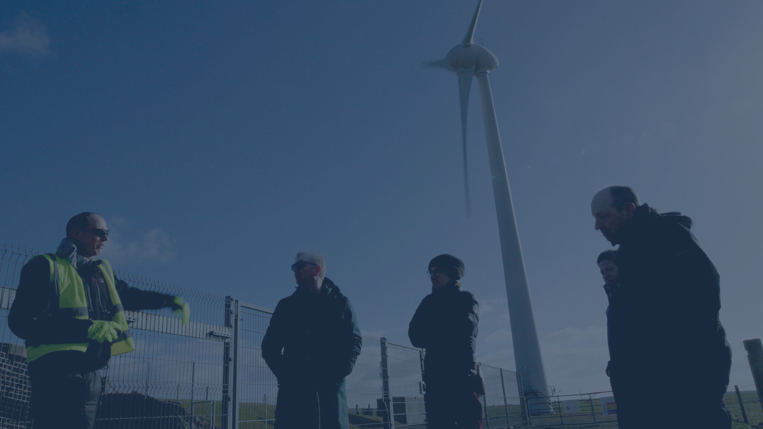 People talking with wind turbine in background