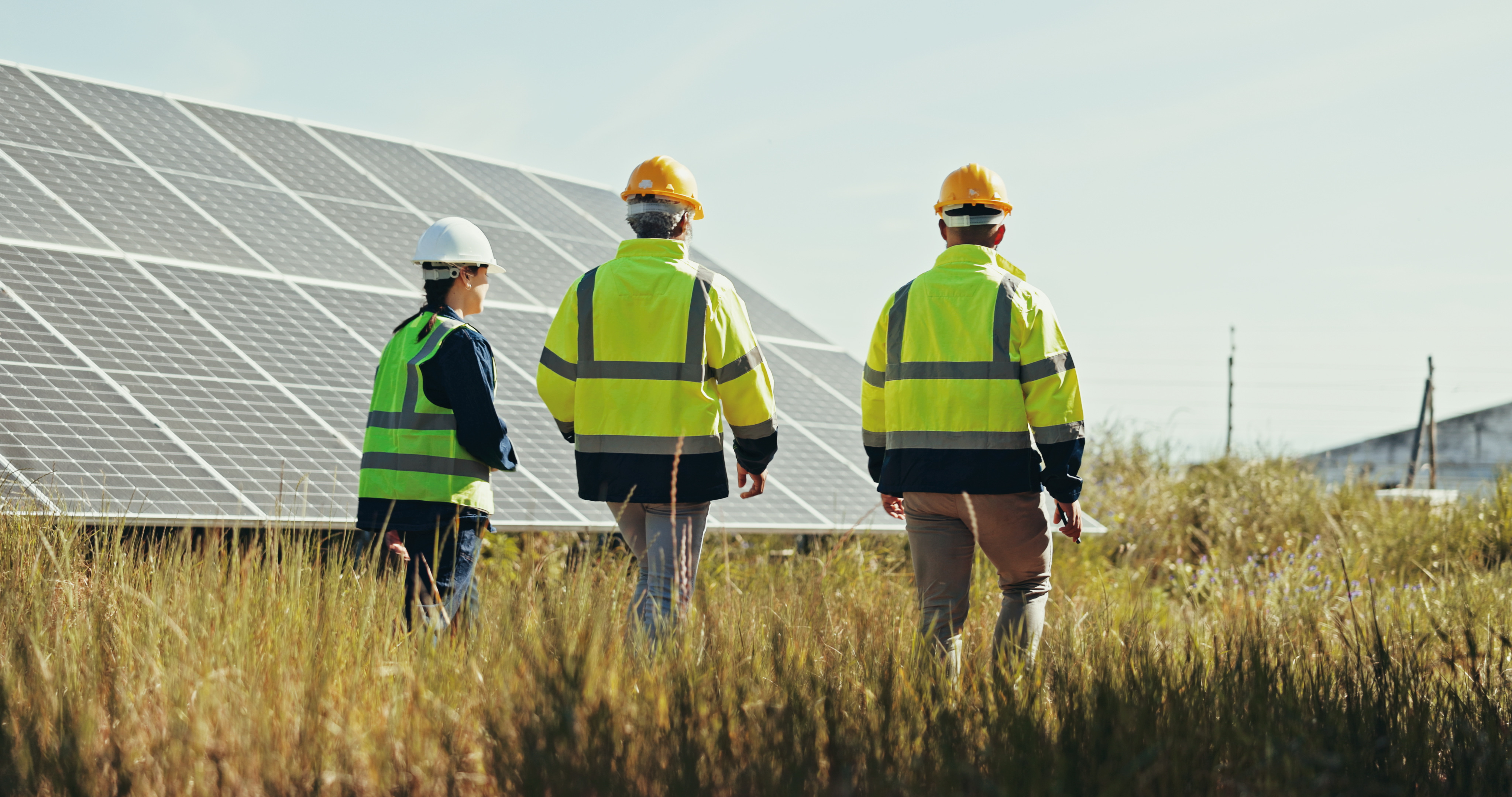 People in high-vis next to solar panel